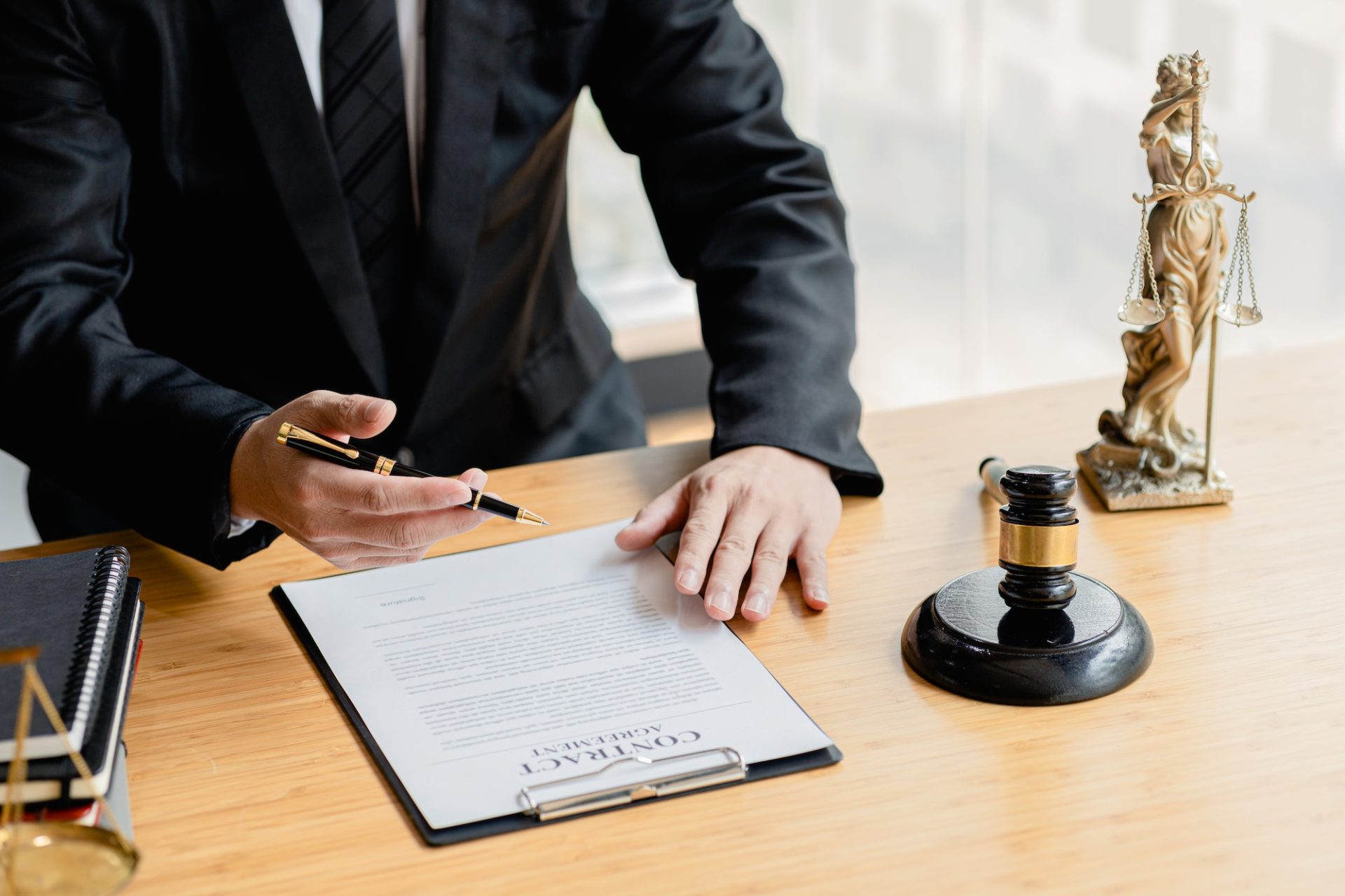 a lawyer sits in his office on a table with a small hammer to beat the judges desk in court e1675758128107